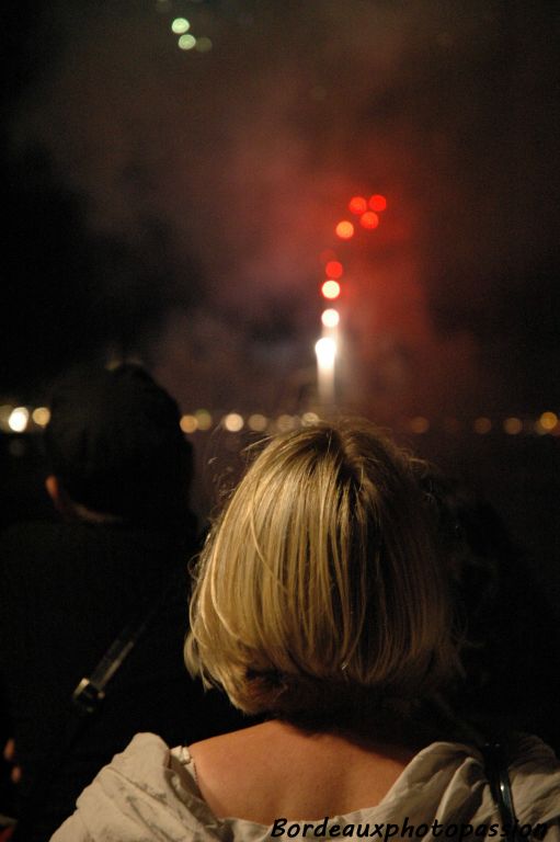 Tous les feux d'artifice ont été tirés depuis la Garonne à part une fusée qui semble sortir tout droit du crâne de cette dame blonde.