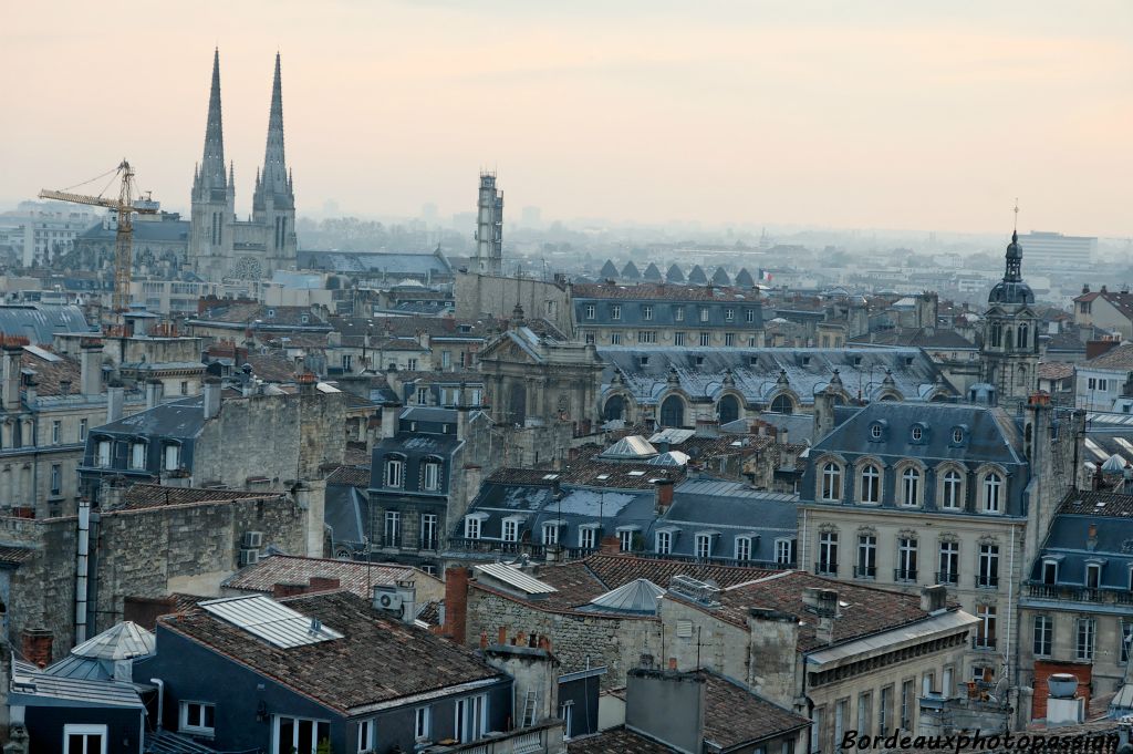 On reconnaît presqu'au premier plan les toits d'ardoise des immeubles du XVIIIe des allées Tourny. Juste derrière, l'église baroque Notre Dame. Au fond, l'ancienne tour de Gaz de France avec les flèches de la cathédrale Saint André.