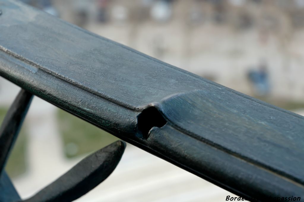 Ce trou dans le garde-fou n'a pas été rebouché au moment de la restauration de la statue qui est au-dessus. C'est une des traces de balles tirées sur un franc-tireur ennemi posté là-haut à la Libération.