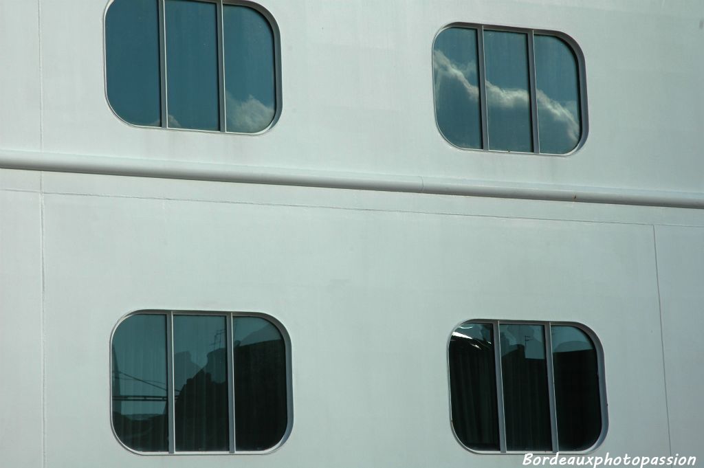 Le ciel et la façade des quais se reflètent dans les vitres du navire.