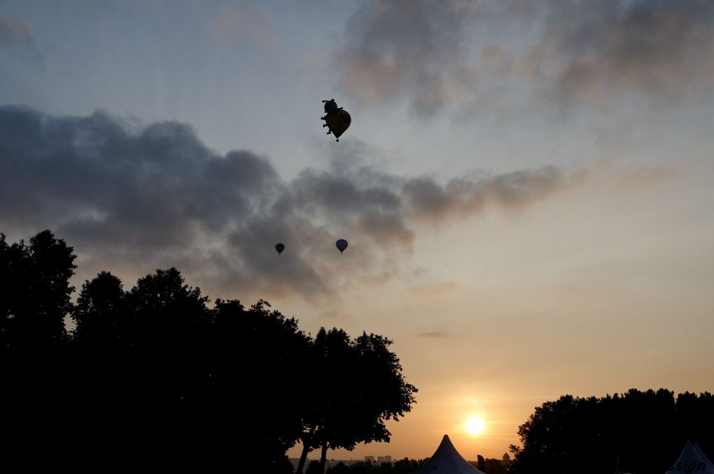 A contrejour face au soleil levant, les montgolfières perdent un instant leurs couleurs.
