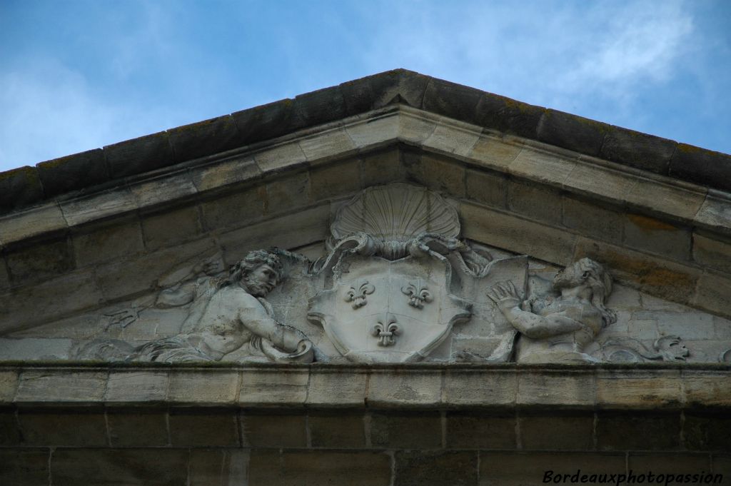 Coté place, un fronton encadre le symbole de la royauté et deux dieux marins étendus évoquant le fleuve et l'agriculture.