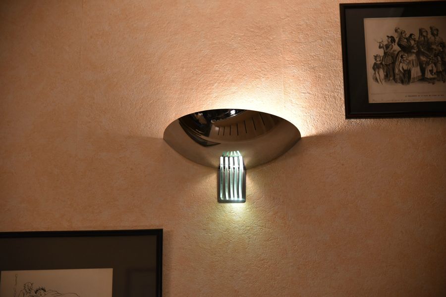 Une applique murale entièrement en métal chromé avec peu de décoration.