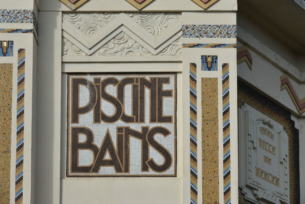 Une décoration stylisée en mosaïque typique de l'époque Art Déco indique "Piscine Bains".