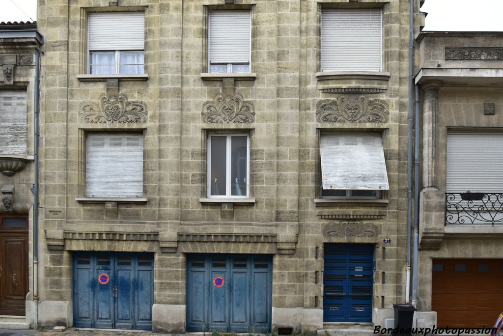 Maison à deux étages avec panneaux décoratifs chargés contrastant avec les appuis de fenêtre très simplistes.