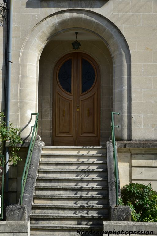 Escalier raide amenant au perron. La porte en bois a deux battants 