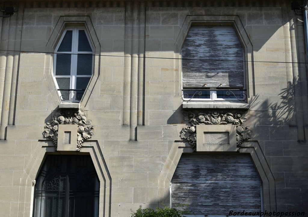 Les baies à pans coupées sont mises en évidence par un rainurage à plat. 3 faisceaux en bâtonnets dégradés rythment la façade.