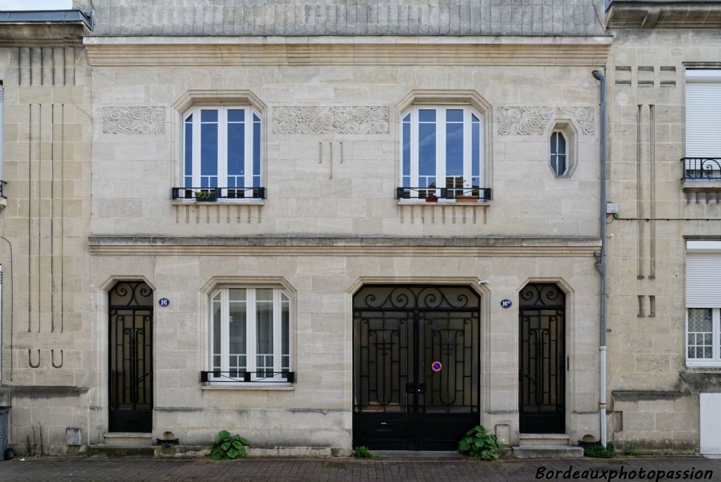 Large façade avec toutes les ouvertures à pans coupés et mises en valeur par un rainurage concave.