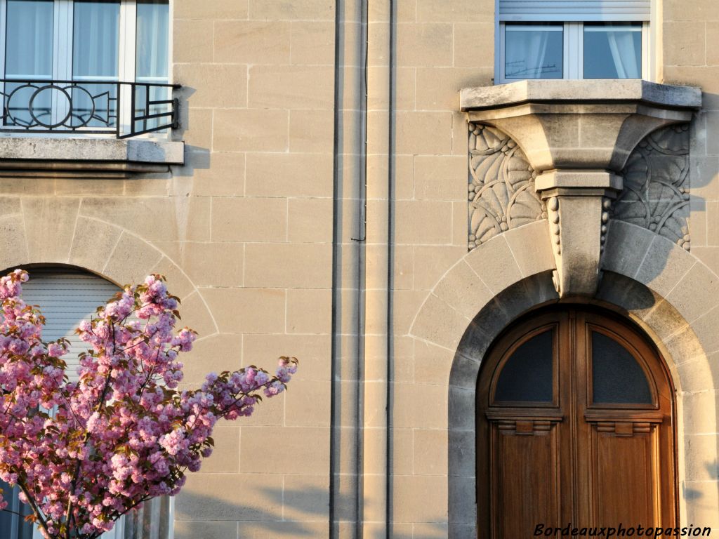 Sous la fenêtre, la corbeille est mise en valeur par un méplat de grosses fleurs. Elle rejoint la clé de voûte de la porte d'entrée formant "une trompe d'éléphant".