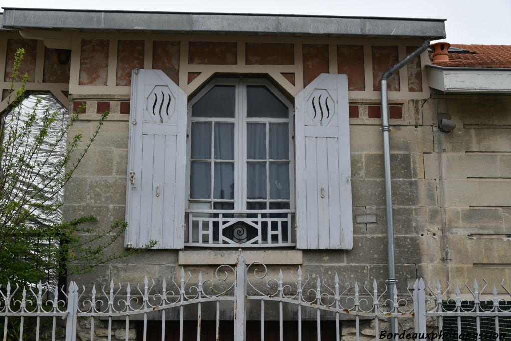 Fenêtre à pans coupés avec garde-corps en bois et ferronnerie.