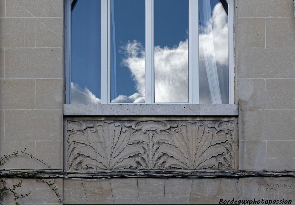 Large panneau décoratif végétal sous une fenêtre à l'étage.