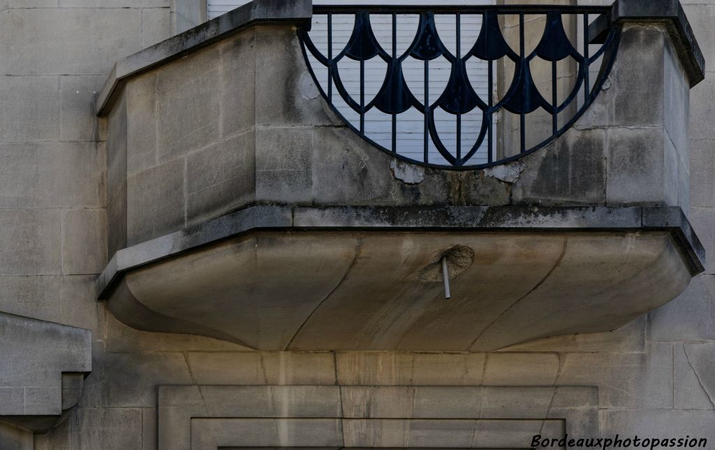 Large balcon ajouré  où la ferronnerie reprend les lignes droites et les courbes de la pierre.