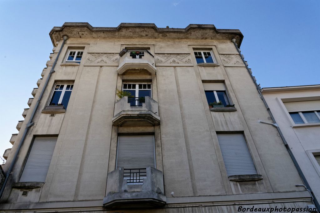 Au 67 rue Perey, tout près du boulevard, un immeuble Art Déco en béton se dresse sur 3 étages. Les murs lisses se terminent par un immense auvent à redents.