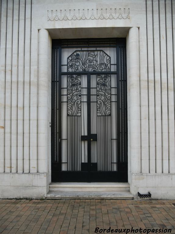 Ferronnerie exceptionnelle de la porte avec pans coupés, rappels des pilastres et fleurs stylisées. Linteau avec frise à feuillage en méplat .