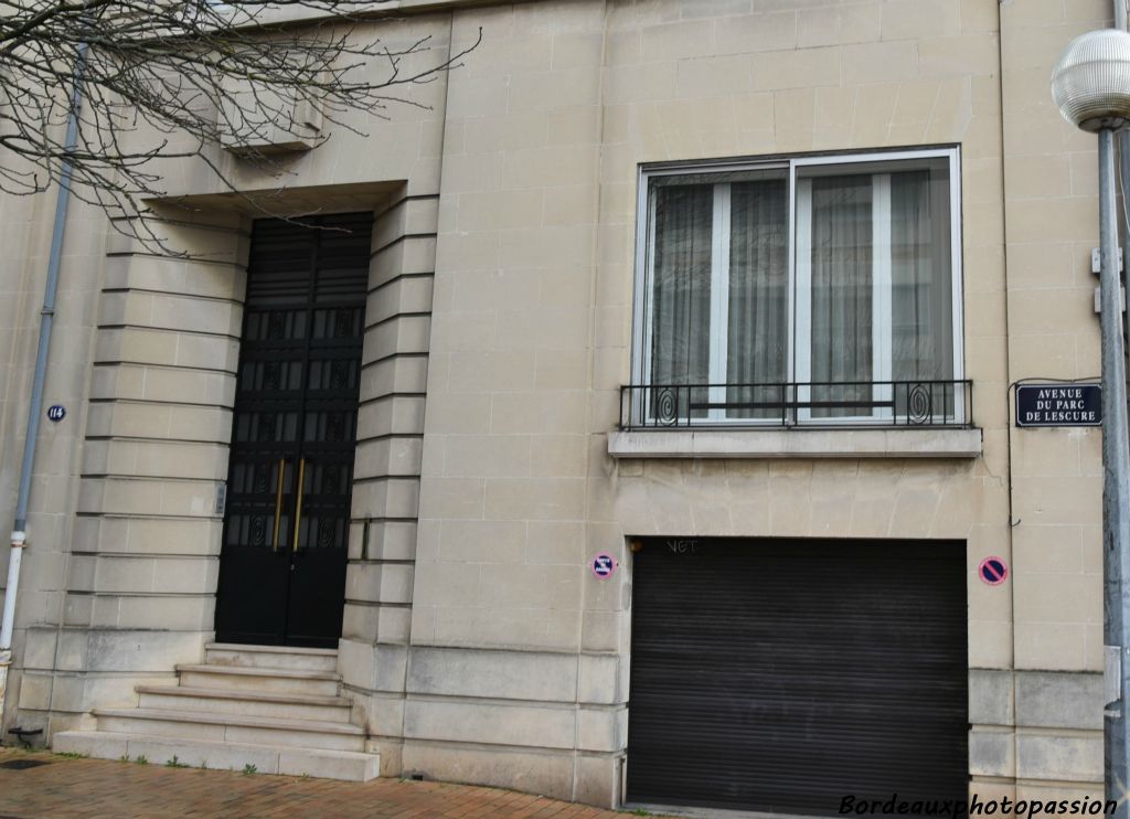 Monumentalité atténuée par le pan coupé de l’aile droite et par les grilles en fer forgé de la porte et fenêtre rez-de-chaussée.