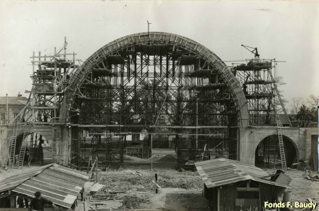 Jacques D'Wells qui poursuit le travail de Jourde, construira une grande arche qui servira d'entrée monumentale côté boulevards (Antoine Gautier à l'époque... Du maréchal Leclerc de nos jours). À cette occasion sera utilisé pour la 1ère fois en France, un échaffaudage métallique.