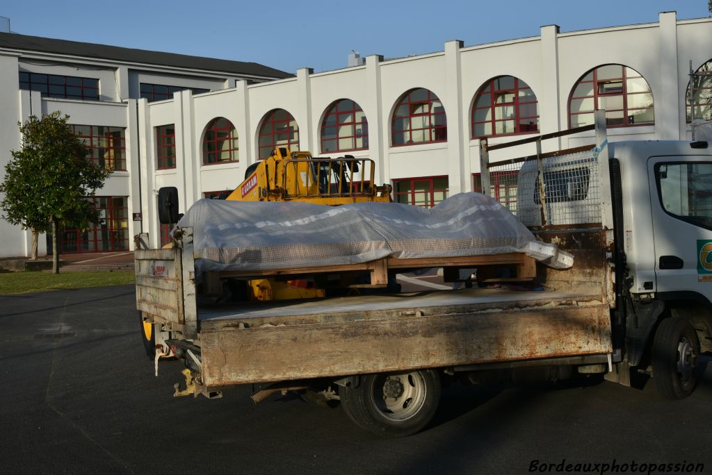 Un chariot élévateur soulève délicatement un mystérieux colis posé sur un support en bois.