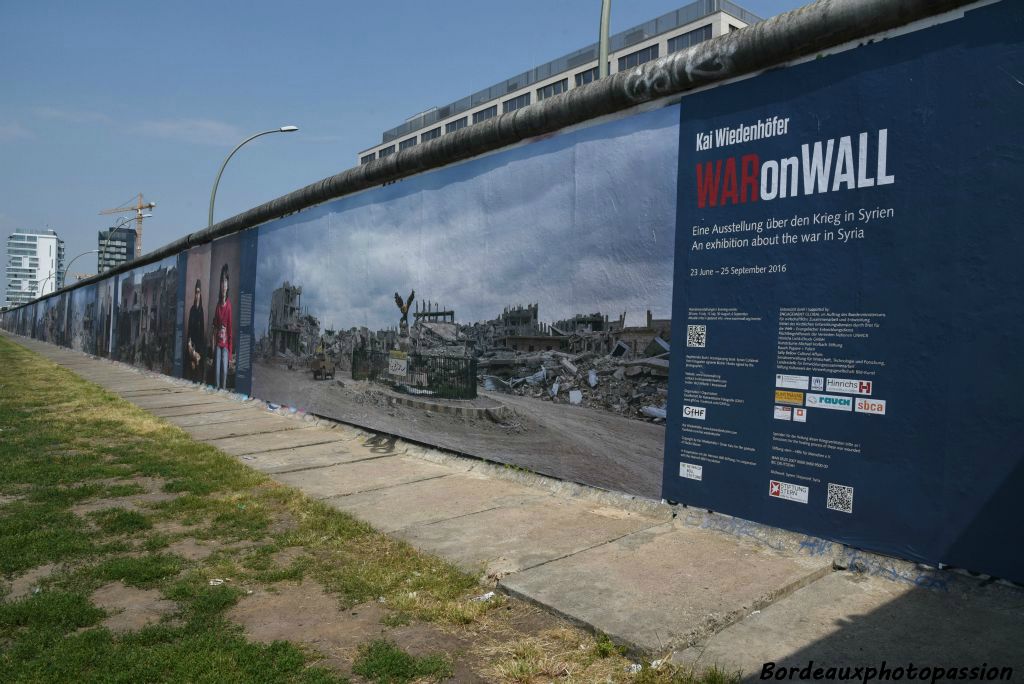 Sur l'autre face du mur, une exposition photo en grand format montre les dégats de la guerre en Syrie.