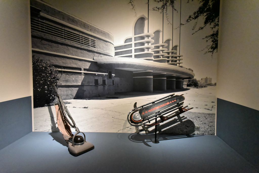 Aspirateur-balai modèle n° 150 vers 1936 Henri Dreyfuss (1904-1972) et luge Skippy Sno-Plane. En arrière-plan le Pan-Pacific Auditorium de Los Angeles Wuderman & Becket architectes 1935