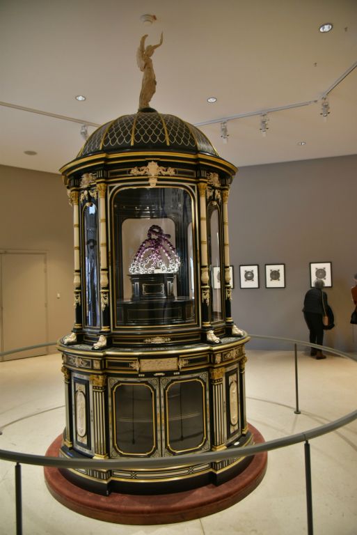 Dans une vitrine du XIXe siècle est présentée une petite sculpture de perles violettes inspirée du chrysanthème japonnais.