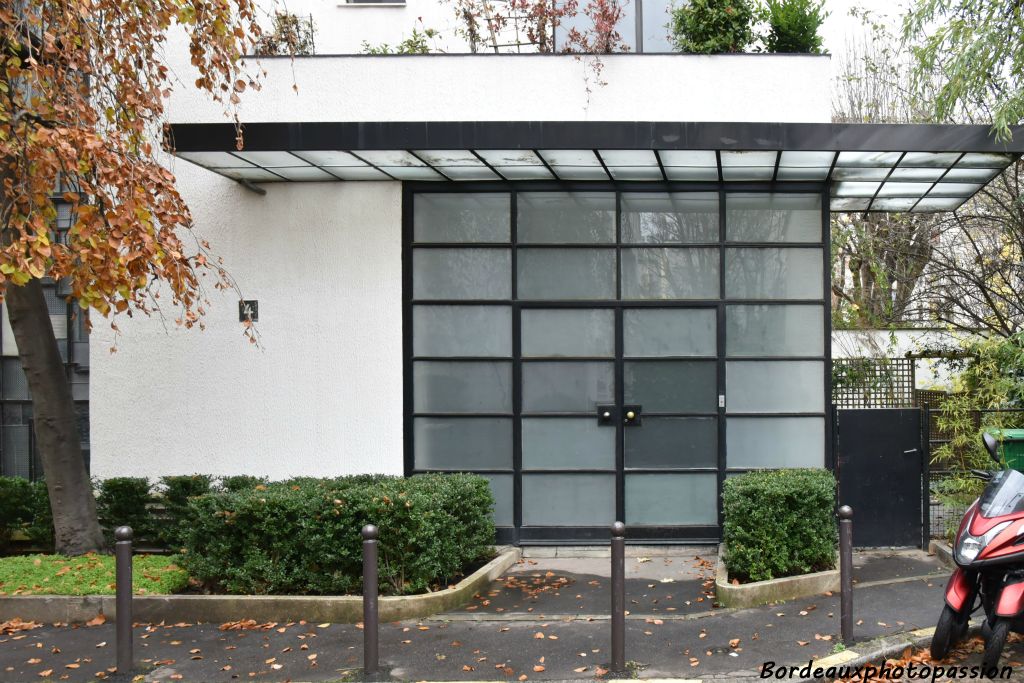 Une large porte vitrée sous un auvent donne accès au vestibule.