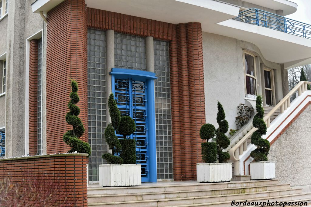 Plus près on perçoit mieux le raffinement et l’originalité du traitement de la façade. L’architecte a joué sur tous les palettes possibles : retraits divers, piliers ronds, obliques de l’escalier, ferronnerie, couleurs variées des revêtements.