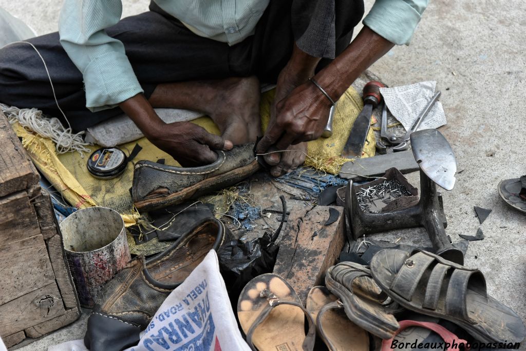 Cordonnier au travail. Il répare toutes les chaussures !